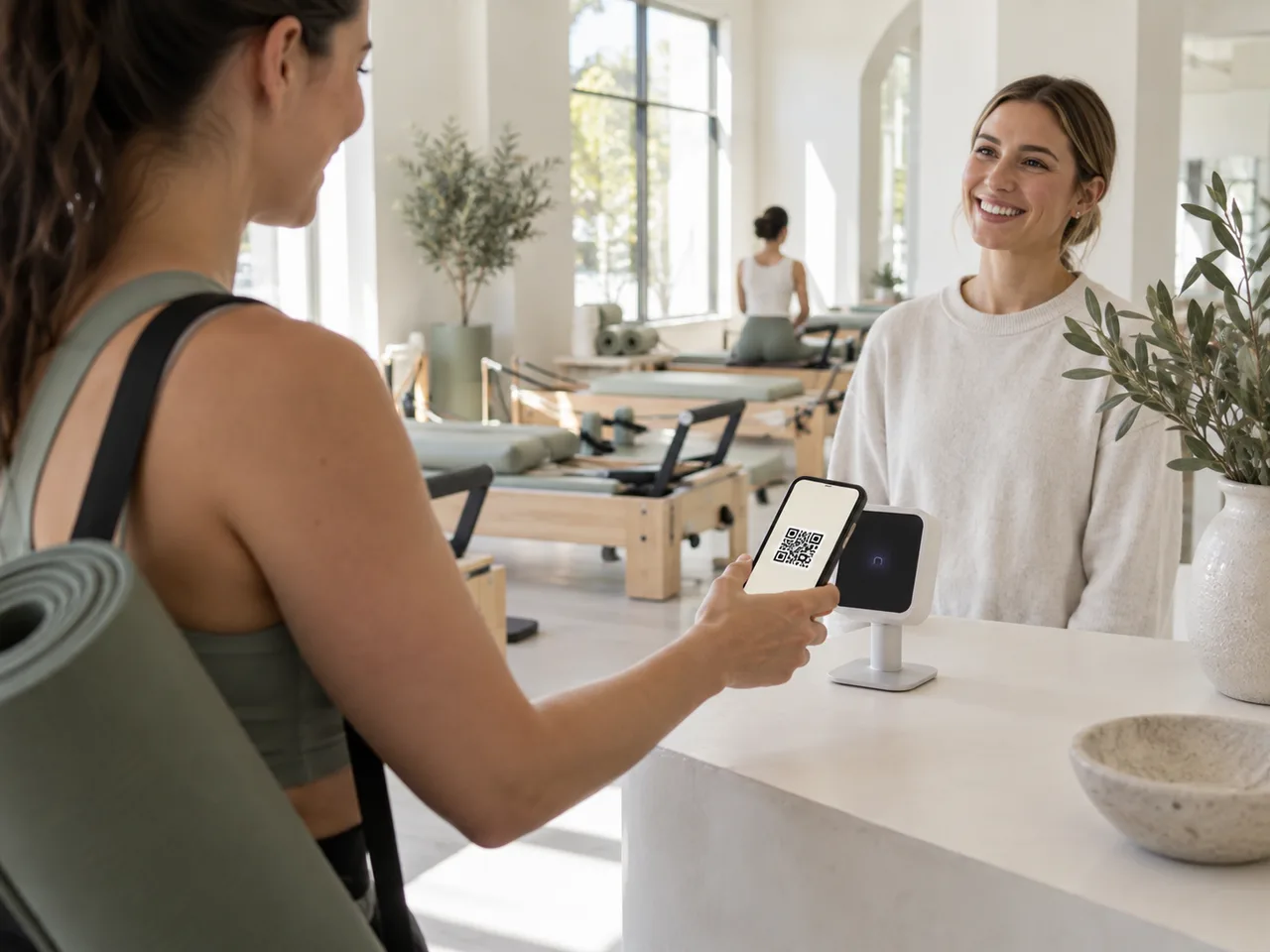 Member checking in with a phone at a sunlit Pilates studio